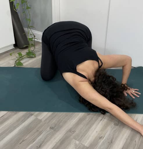 alt="woman doing puppy pose with side stretch"